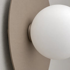 Gros plan sur le disque en acier laqué mat et le globe de verre opalin