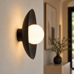 Applique disque en métal et globe de verre allumée sur un mur d'entrée