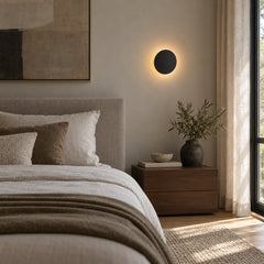 Lampe murale ronde allumée au-dessus d'une table de chevet dans une chambre lumineuse