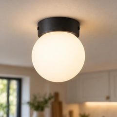 Plafonnier boule en verre allumé vu de près au plafond d'une cuisine claire