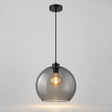 Suspension verre fumé Nevora allumée, globe gris et monture noire sur fond neutre