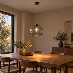 Suspension globe verre fumé allumée au-dessus d'une table en bois de salle à manger